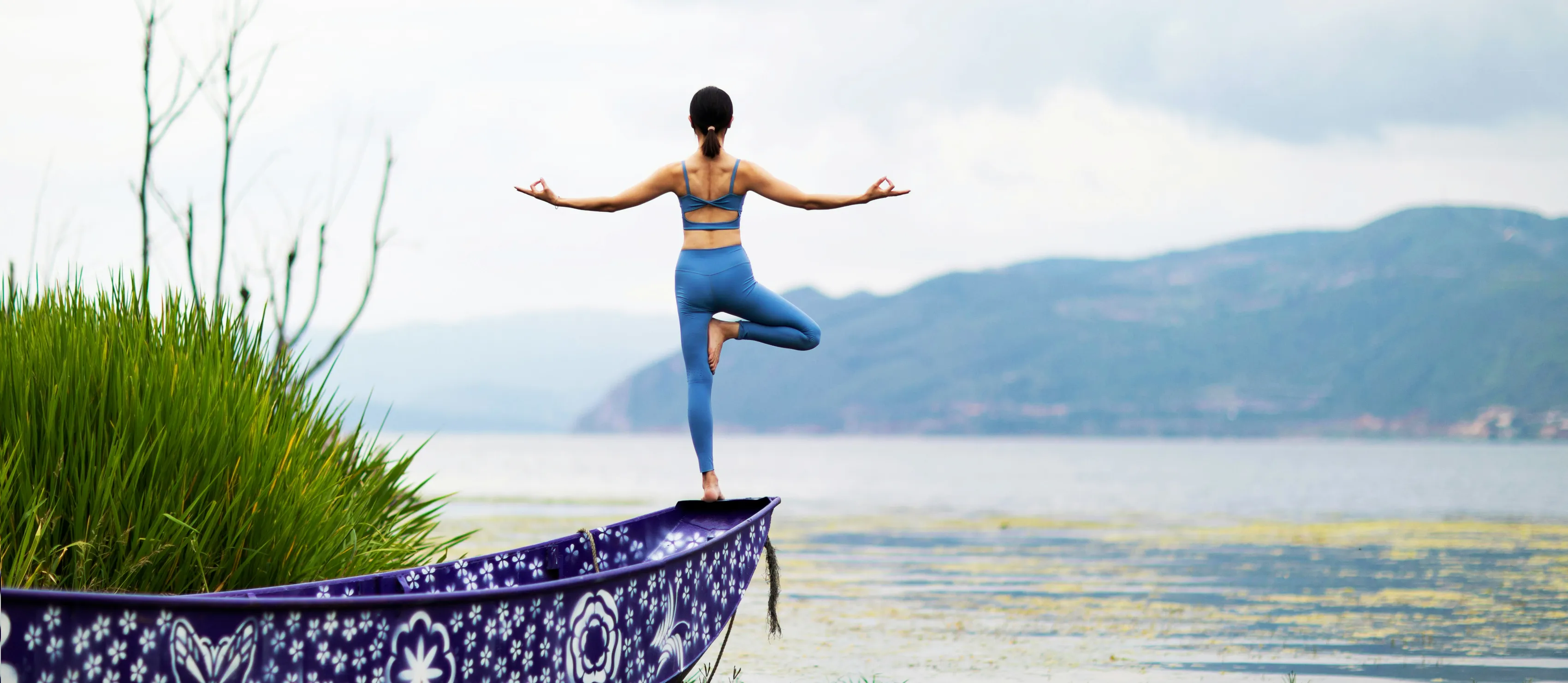 Woman practising tree pose on canoe