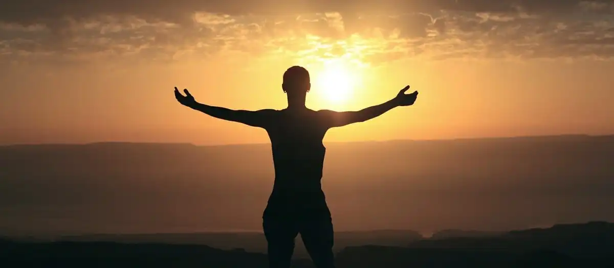 Man practising yoga in front of beautiful sunset.