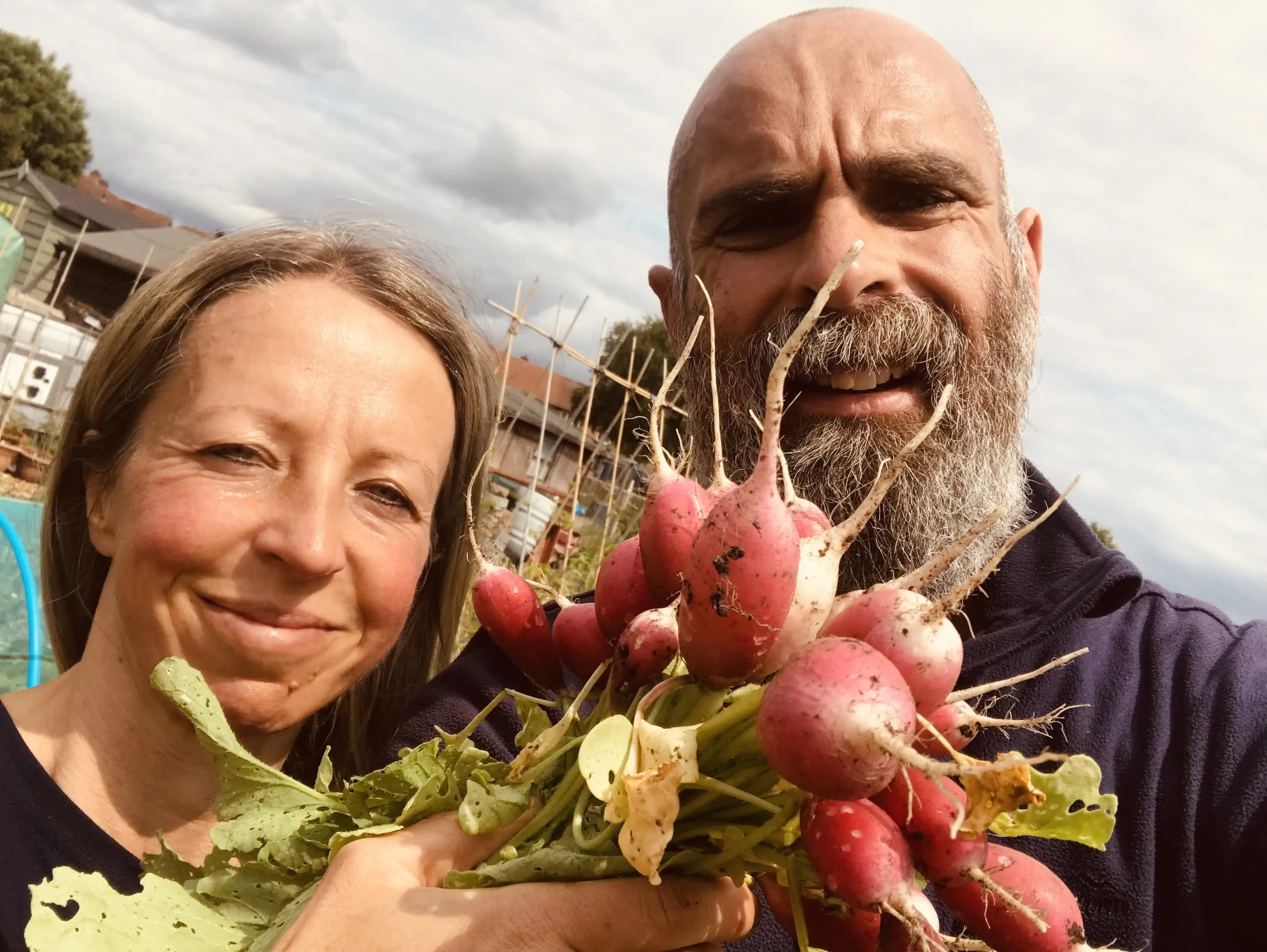 Two gardeners holding radishes on the allotment