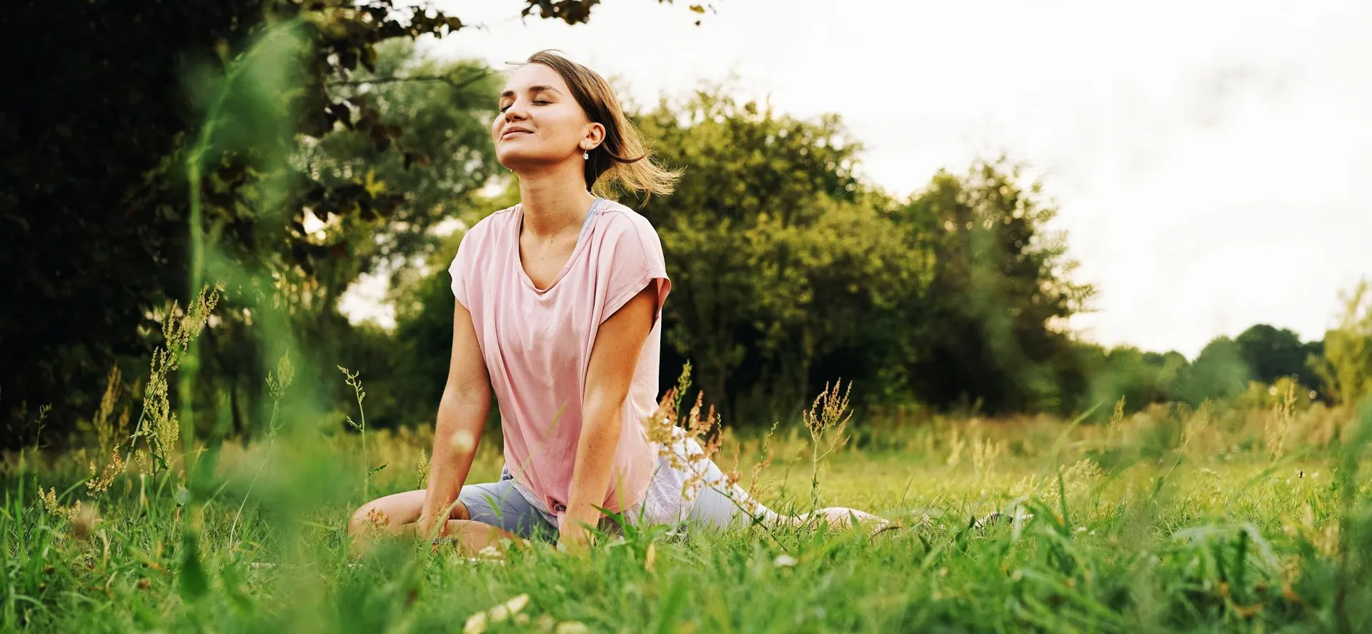 Woman doing yoga in a green field.