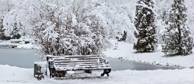 Park bench covered in white snow.