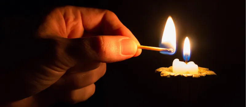 Hand lighting a candle.